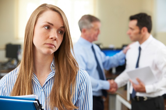 Woman at work excluded from men's conversation taking place behind her